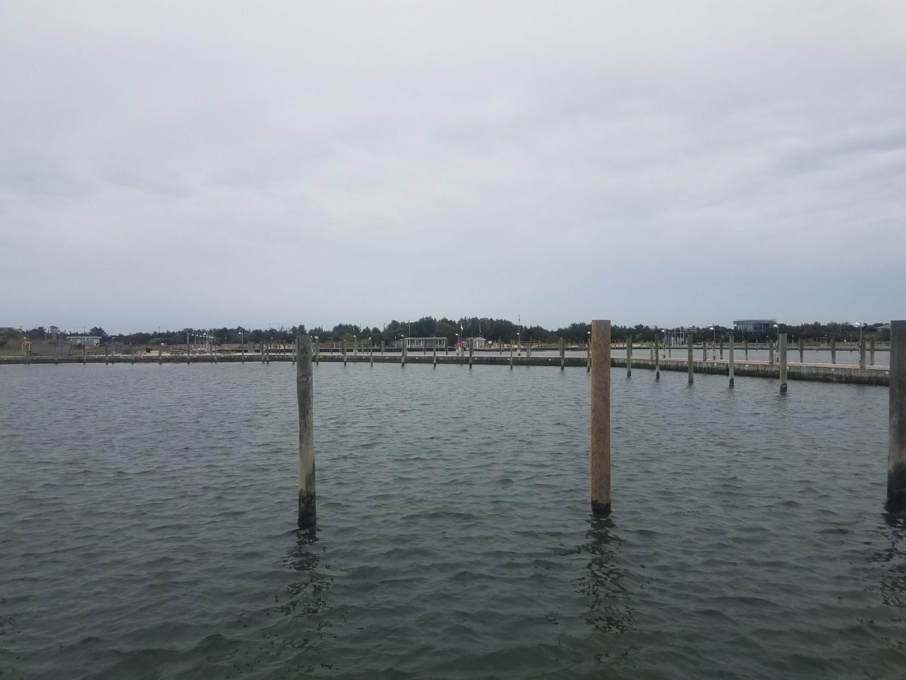 Empty marina slips and wooden pilings under an overcast sky before boats return for the season.