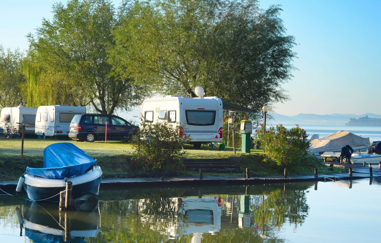 Wooden dock, small boats, and waterfront trailers beside calm water