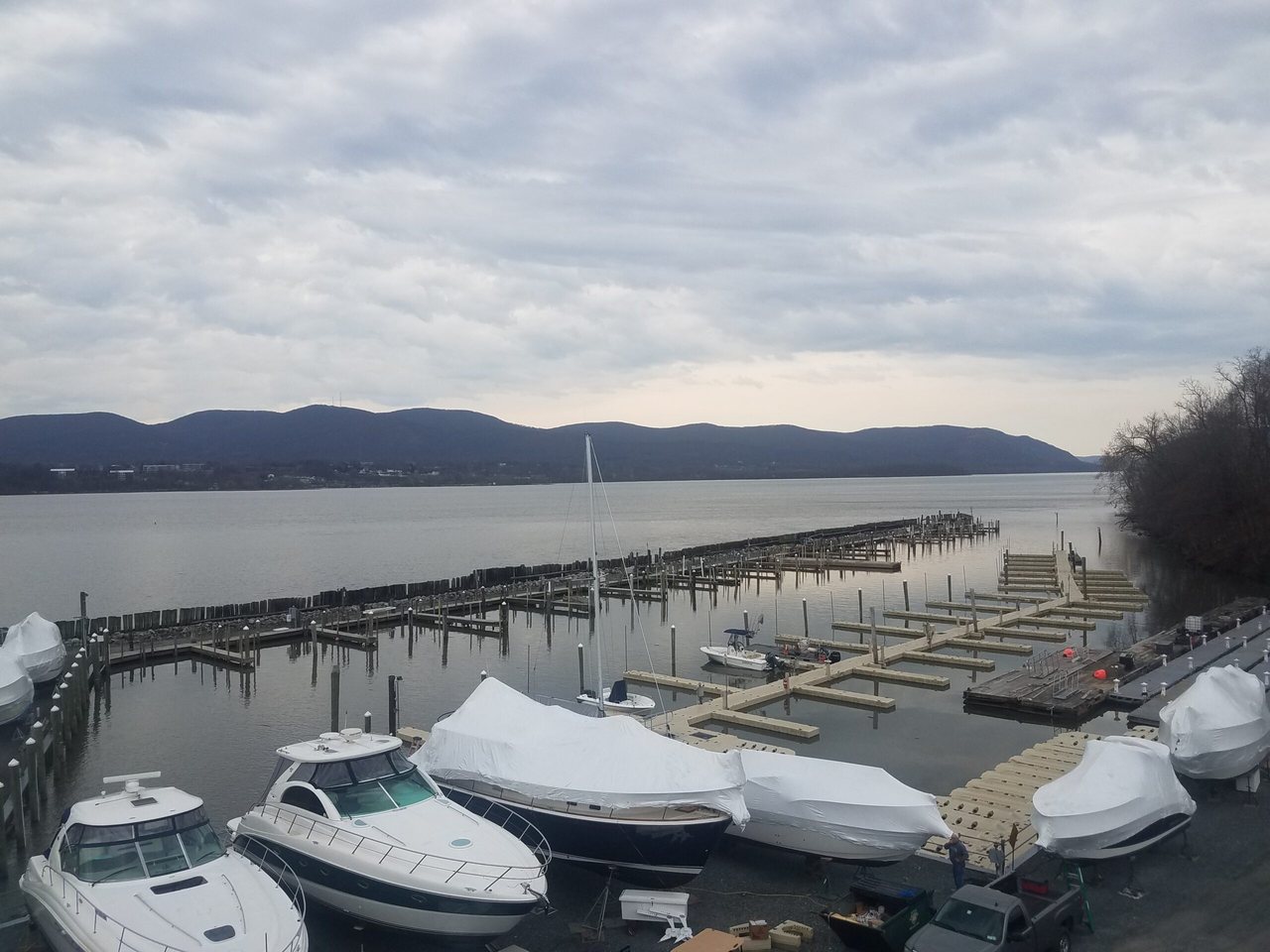 Shrink-wrapped boats in marina dry storage beside empty docks under an overcast sky