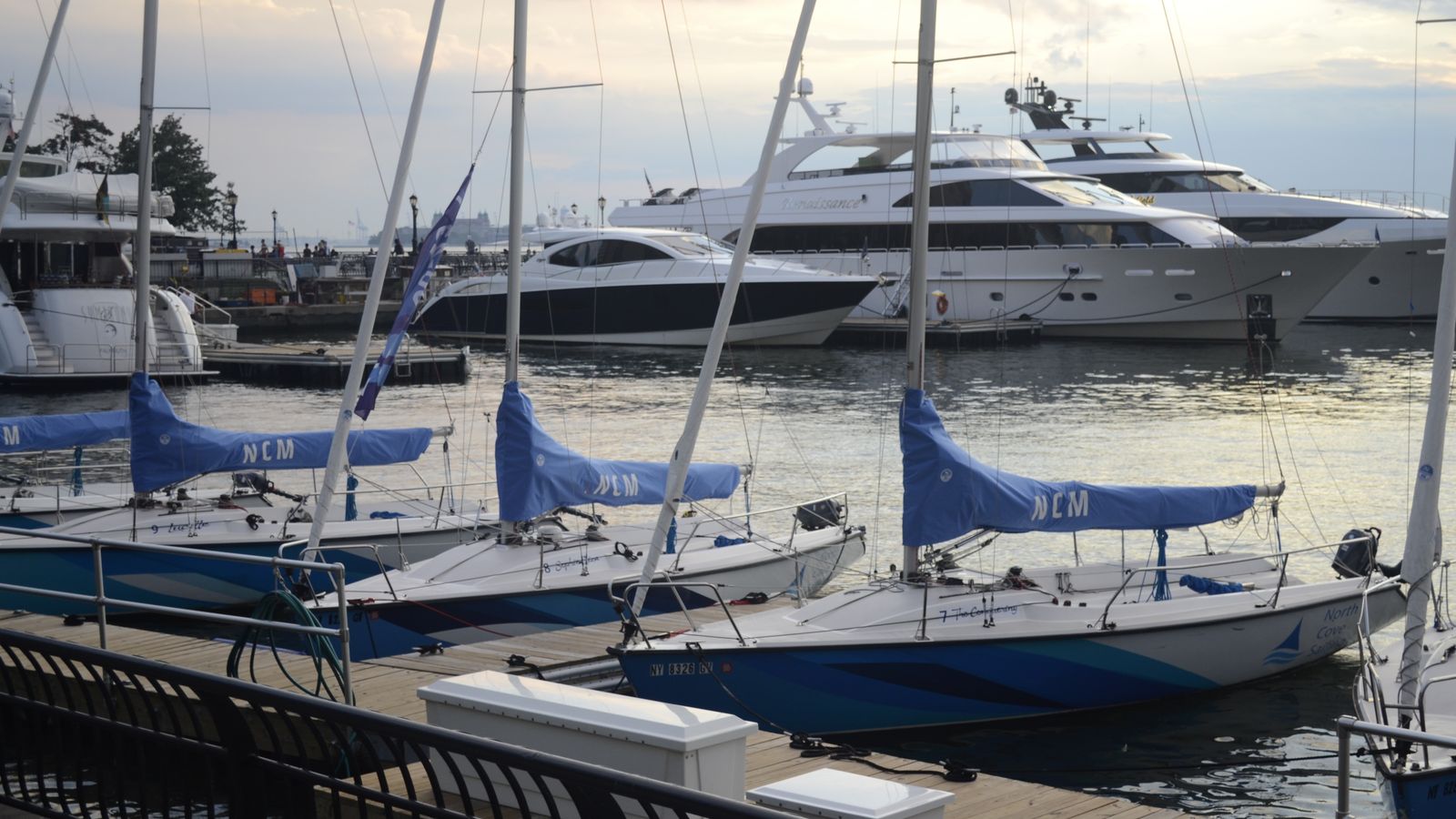 Sailboats and motorboats moored at docks in a marina.